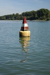 Red and white buoy marking the Lauter river mouth into river Rhine on a sunny day, easternmost point of Metropolitan France and southernmost point of Rhineland Palatinate (Germany)
