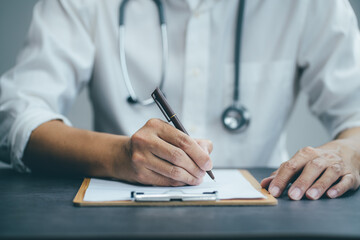 Doctor working writes notes on the clipboard at hospital. Health care, insurance and help concept