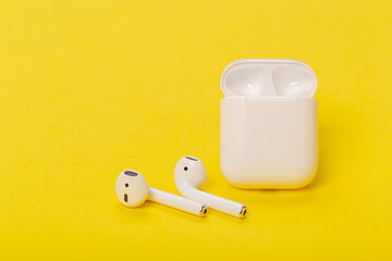 wireless bluetooth headphones with charging case on a yellow background. The concept of modern technology.