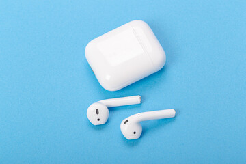 wireless bluetooth earphones with charging case on a blue background. The concept of modern technology.