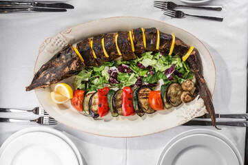 grilled Whole sturgeon Fish with lemon and grilled vegetables on plate