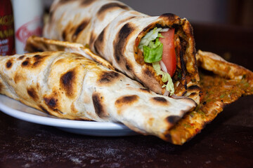 Turkish lahmacun with lettuce and tomato, wrapped as a wrap on a plate