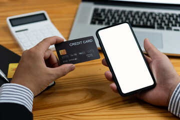 online payment concept A woman uses a credit card and a white-screened cell phone to shop and pay via interbank branches.