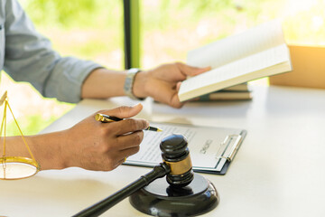 Judge or lawyer working on paperwork behind the weight of justice, a male lawyer working at a desk in an office. Emphasis is placed on the level of justice that the hammer is placed in front of the sc