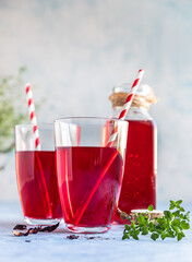 Hot hibiscus or karkade tea in glass with herb and dry tea leaves. Vitamin herbal tea for cold and flu.