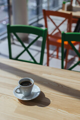 Cup of black coffee on a rustic wooden table in a cafe.