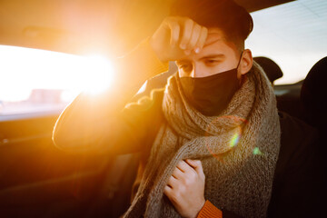Young man in protective sterile mask on a back seat coughing. Covid-2019. Healthcare, virus, allergy concept.