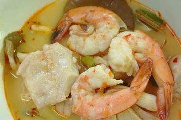 boiled river shrimp and bass fish with mushroom in Thai spicy soup or tom yum kung on bowl
