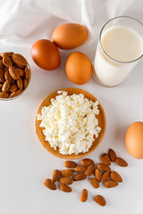 Protein food on a white background - cottage cheese, eggs, nuts. A set of healthy foods for a balanced diet.