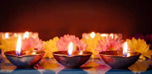 Happy Diwali. Traditional symbols of Indian festival of light. Burning diya oil lamps and flowers on red background.