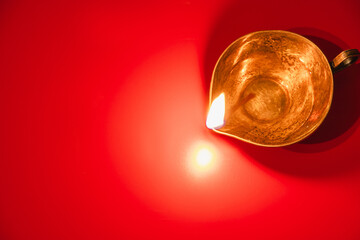Burning diya oil lamp on red background. Celebrating the Indian traditional festival of light. Happy Diwali.