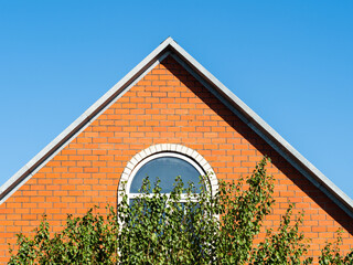 blue sky over brick gable wall with window of house on sunny day