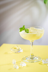 fresh banana and coconut tropical cocktail in a glass over yellow background