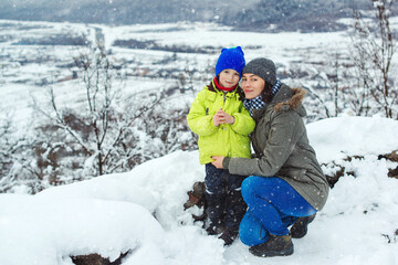 Fototapeta na wymiar Mother and child on snowy winter walk. Family enjoying beautiful winter nature. Snowy winter season.