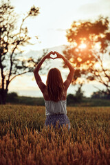 Woman in nature holding heart-shape symbol made with hands.