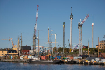 Obraz premium Sailboat masts, towers and cranes in the harbor an d docks of the island Beckholmen in Stockholm an color full autumn day