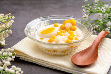 Pumpkin (white and yellow) rice dumpling in coconut milk (Bua Loy) in transparency bowl on wooden table. Delicious Thai dessert.