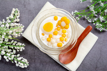 Pumpkin (white and yellow) rice dumpling in coconut milk (Bua Loy) in transparency bowl on wooden table. Delicious Thai dessert.