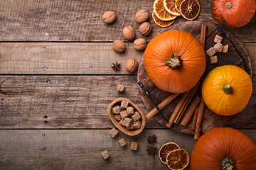 Pumpkin. Autumn food background with cinnamon, nuts and seasonal spices on rustic background. Cooking pumpkin or apple pie and cookies for Thanksgiving and autumn holidays. Top view with copy space.