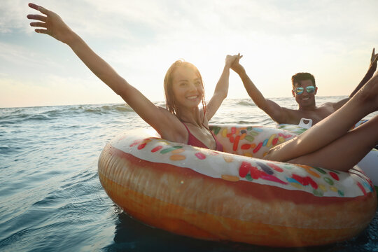 Happy couple with inflatable rings in sea
