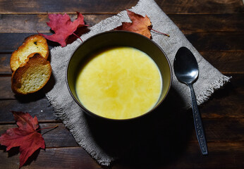 Pumpkin soup puree in a brown plate on a wooden table