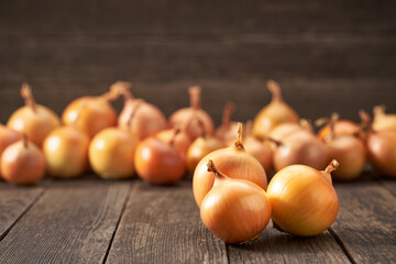 Raw whole onions on a wooden table, selective focus.