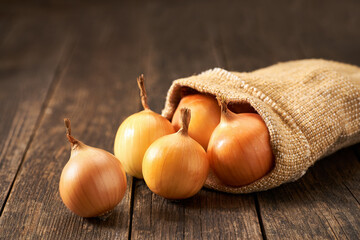 yellow onions on a rustic wooden table, selective focus.