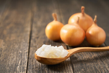 Chopped onion in a wooden spoon on a rustic table, copy space for text.