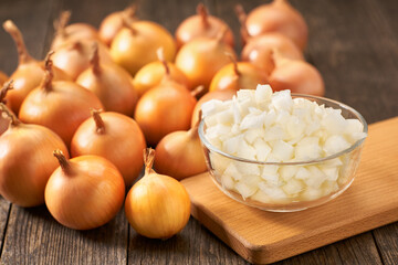 chopped onions in a glass bowl on a wooden table.