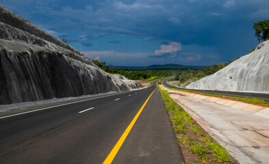 down and uphill road cut through tropical forest in Thailand