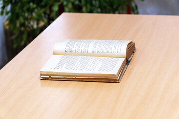 An open book on a wooden table. Selective focus