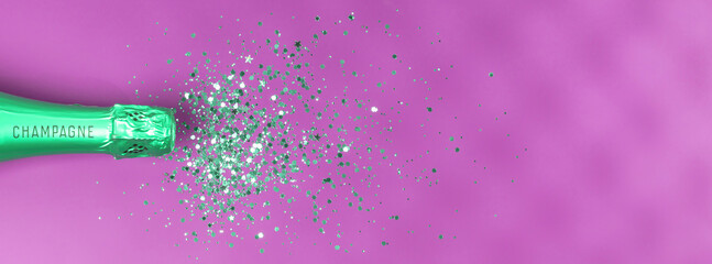 Bottle of champagne and confetti on pink background, top view.
