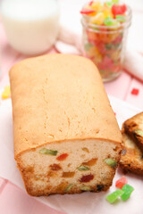 Delicious cake with candied fruits on pink table, closeup