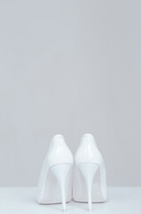 Closeup of a pair of white high heel womens shoes isolated on gray background