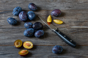 whole and cut plums with knife on a table