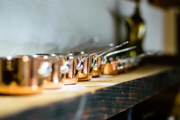 Fototapeta na wymiar Small copper pots on a wooden ledge at a restaurant