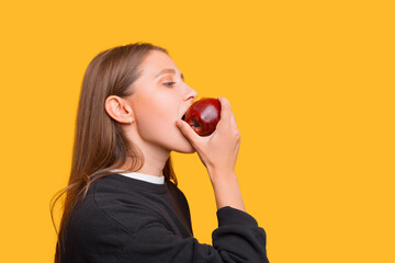 Pretty girl is holding a red apple and eating from it.