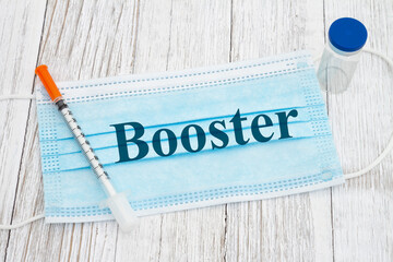 Booster message on medical face mask with needle and vaccine bottle