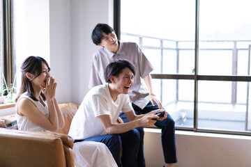 家でテレビゲームをする若い男女