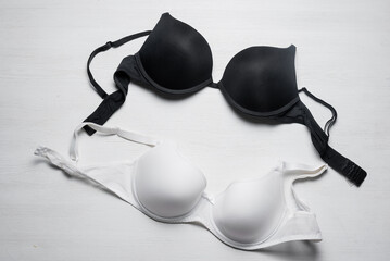 Black and white bra on the white table background. Top view. - obrazy, fototapety, plakaty