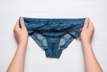 Woman holds in hands a panties on the white flat lay table background.