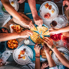Above top view of hands picking food from the center of  the table - friends enjoy lunch together - concept of people and food celebration - friendship caucasian group celebrate and enjoy brunch