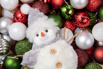 Obraz premium Cute white snowman and Christmas toys on a red background. Beautiful new year card