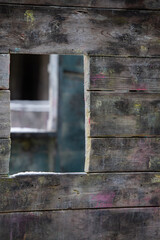 depth perception looking into one open rectangular window of abandoned cabin in woods with other open windows behind all windows lined up with framing and open space for type and logo vertical format 