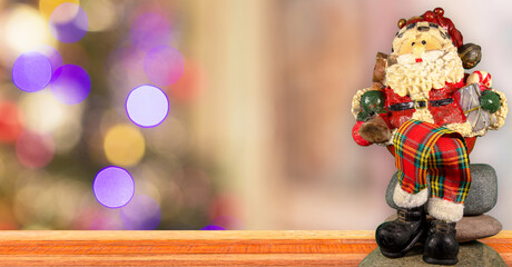 Naklejka premium Santa Claus doll sitting on the table and background with Christmas lights.