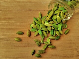 close up view of fresh green cardamom  (sabz eliche in Urdu)over a wooden texture .