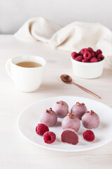 Homemade truffles with raspberries on a white plate. Sugar, gluten and lactose free, vegan.
