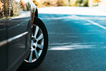 Car on asphalt road on autumn day at forest or park.Selective focus,copy space.Toned.