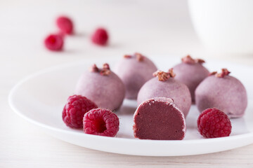 Raspberry truffles on a white plate. Sugar, gluten and lactose free, vegan.