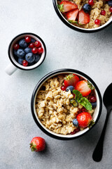 Tasty oatmeal with berries in bowl on white background